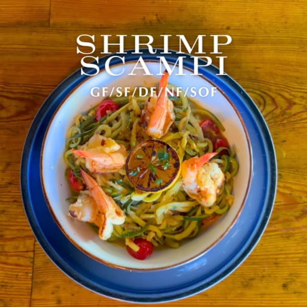 Alyce's Shrimp Scampi features zucchini noodles, cherry tomatoes, shrimp, and a grilled lemon slice.
