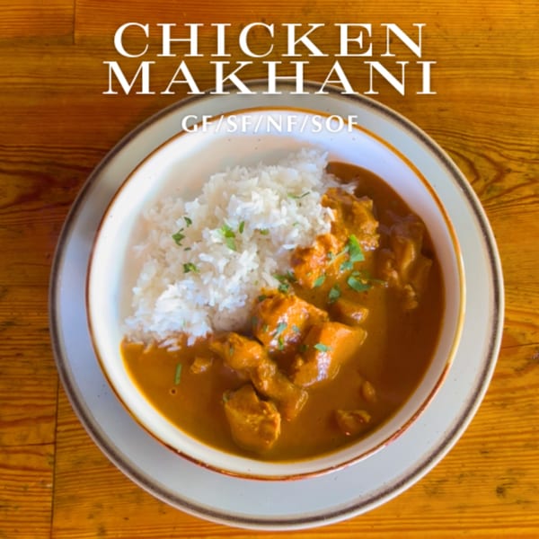 A bowl of Alyce's Chicken Makhani with white rice, garnished with fresh herbs on a wooden table.