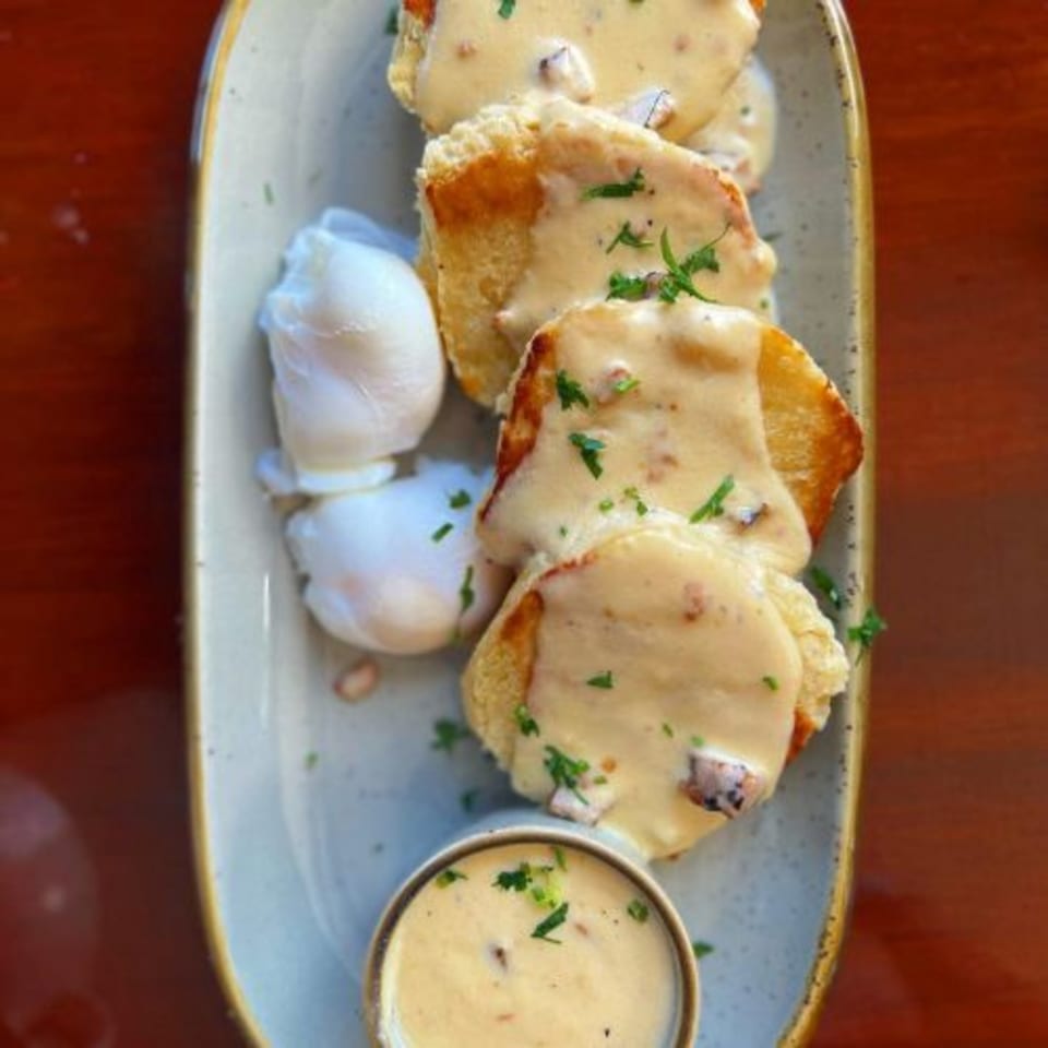 Alyce's biscuits and gravy with poached eggs and a side of gravy on a light blue plate.